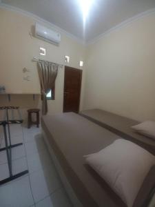 a room with a bed and a table and a window at Niti Guest House in Tegalan
