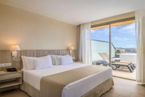 a hotel room with a large bed and a balcony at Barceló Santiago - Adults Only in Puerto de Santiago