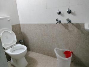 a bathroom with a toilet and a trash can at Hotel Padamaa Palace in Varanasi