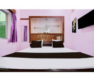 a bedroom with a large white bed with black pillows at Hotel Padamaa Palace in Varanasi