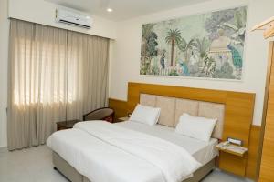 a bedroom with a bed and a painting on the wall at Pearl Inn in Dhārwād