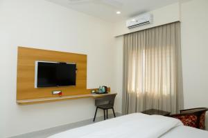 a hotel room with a bed and a tv on a wall at Pearl Inn in Dhārwād