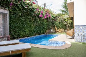 a backyard with a swimming pool and a hedge with flowers at Casa Mara Dakar in Dakar