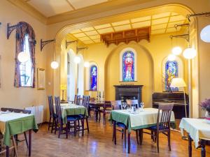 a dining room with tables and chairs and stained glass windows at The Convent Leenane in Leenaun