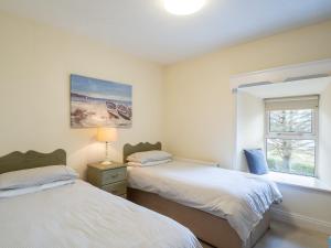 two beds in a room with a window at The Convent Leenane in Leenaun