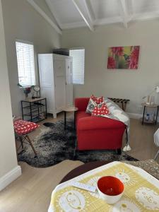 a living room with a red chair and a couch at Island Studio Apartment in Knysna