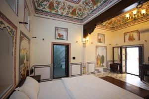 a bedroom with a bed and a ceiling with paintings at Haveli Kesar Vilas in Chāran ki Dhāni