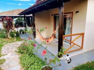 a cat sitting outside of a house with a hammock at POUSADA ACONCHEGO CHAPADA in Alto Paraíso de Goiás