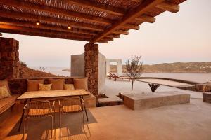 a patio with a table and chairs and a view of the water at Mykonos Dunes Villas in Mikonos
