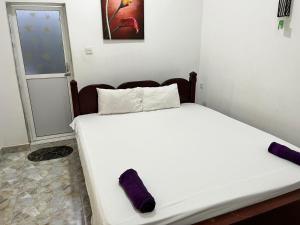 a bedroom with a white bed with purple pillows at BeachBay Guest House in Negombo