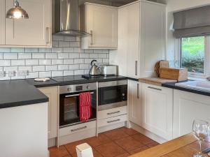a kitchen with white cabinets and a stove top oven at Mimosa - Uk51224 in Swyre