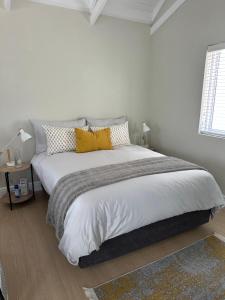 a white bedroom with a large bed with yellow pillows at Island Studio Apartment in Knysna