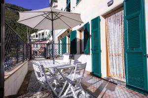 a table and chairs with an umbrella on a balcony at Rio Apartment cà di Euro with parking in Riomaggiore