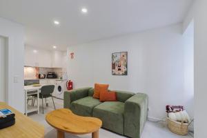 a living room with a green couch and a kitchen at Moradia Bar Sela, By Home Match in Setúbal