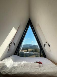 a bed in a room with a large window at TwoTop-Premium Chalet Villa with mountain view in Piatra Fantanele