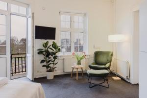 a bedroom with a green chair and a tv in it at Nomad City Hotel - Odense in Odense