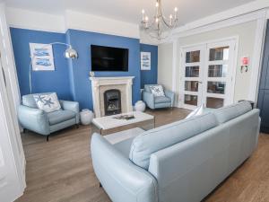 a living room with blue walls and a couch and chairs at Vista Mare 1 in Weymouth