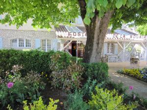 un edificio con un árbol y flores delante de él en Hostellerie de la Bouriane en Gourdon-en-quercy