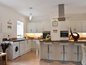 a kitchen with white cabinets and a washer and dryer at Ladybird Cottage in Lochend