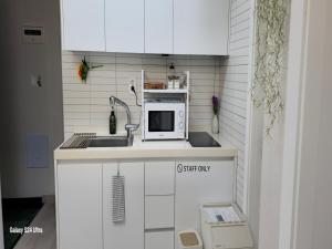 eine kleine Küche mit Spüle und Mikrowelle in der Unterkunft Gate 303 in Seoul