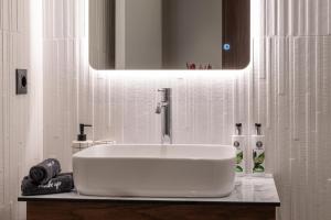 ein weißes Waschbecken in einem Badezimmer mit Spiegel in der Unterkunft CENTRO Suites in Kalamata + 133 Fotos