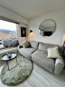 a living room with a couch and a round mirror at Vincenzo appart, Studio Confortable à Nendaz, accès Direct au Télécabine de Tracouet et Parking Souterrain Inclus in Nendaz