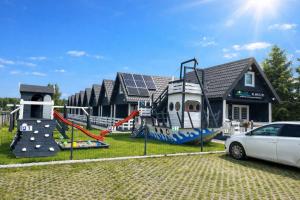 a house with a playground with a car parked in front at Domeczki Blaneczki Wicie - domki letniskowe nad morzem in Wicie