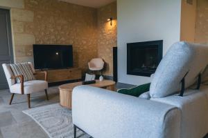 a living room with a couch and a tv at Château La Voûte in Saint-Étienne-de-Lisse