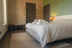 a bedroom with a large bed with white sheets and pillows at Château La Voûte in Saint-Étienne-de-Lisse