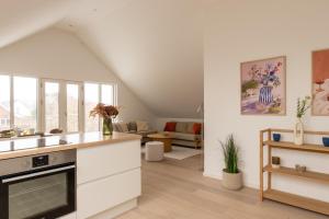 a kitchen with white cabinets and a living room at Sunlit Loft Apartment in Valby with Parking for 8 in Copenhagen