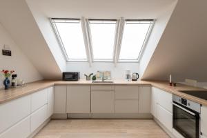 an attic kitchen with white cabinets and windows at Sunlit Loft Apartment in Valby with Parking for 8 in Copenhagen