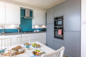 a white kitchen with a table with food on it at Rooftop Hideaway -Central Coastal Flat - Sea Views in Seaton