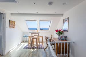a dining room with a table and two windows at Rooftop Hideaway -Central Coastal Flat - Sea Views in Seaton