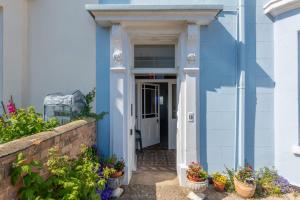 a blue house with potted plants in front of it at Rooftop Hideaway -Central Coastal Flat - Sea Views in Seaton