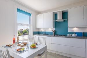 a kitchen with white cabinets and a table with food on it at Rooftop Hideaway -Central Coastal Flat - Sea Views in Seaton +21 photos