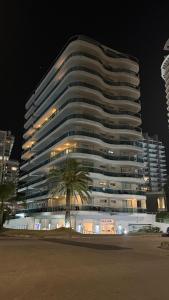 a large building with a palm tree in front of it at Punta del Este, Sol y Luna II, Departamento 301 in Punta del Este