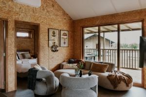 a living room with a couch and chairs and a bed at Dutchen Erfgoedpark De Hoop Glamping, Appartementen & Cottages in Uitgeest