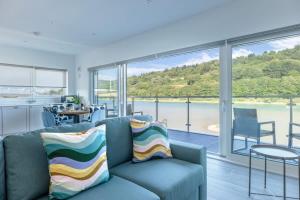 a living room with a blue couch and a large window at River View - Prime River Front Location in Seaton