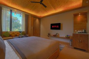a bedroom with a bed and a tv on the wall at ELIVAAS Signature Pine view resort in Sabāthu