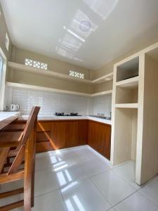 a large kitchen with wooden cabinets and white tiles at Dava Guest House Gianyar in Gianyar