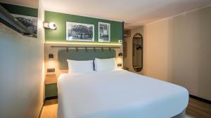 a bedroom with a large white bed in a room at Campanile NATURE - Strasbourg Sud Geispolsheim in Geispolsheim