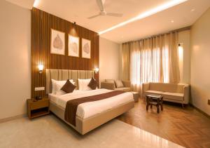 a bedroom with a bed and a couch and a chair at HOTEL NARMADA RESIDENCY in Maheshwar