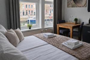a bedroom with a bed with a table and a window at Boutique Hotel De Grote Kade in Goes