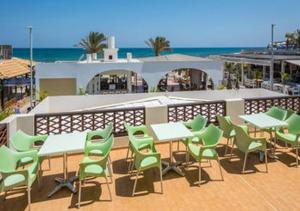 a patio with tables and green chairs and the ocean at Smaragdine Beach Hotel in Stalís +17 photos