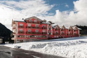 a large red building with snow in front of it at Hotel Continental in Andalo