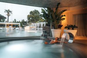 a woman laying in a swimming pool at a hotel at Oasi Blu Sardinia in Santa Margherita di Pula