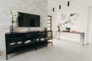 a black entertainment center with a television on a brick wall at סוויטת בית ינאי in Beit-Herut