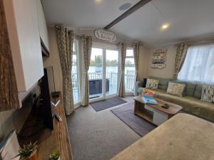a living room with a couch and a table at Nestled beneath the trees is this beauty a 3 bed property with hot tub and stunning views in Tattershall