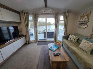 a living room with a couch and a tv at Nestled beneath the trees is this beauty a 3 bed property with hot tub and stunning views in Tattershall