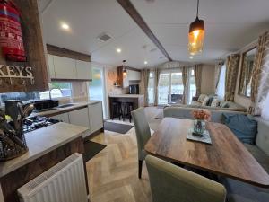 a kitchen and living room with a wooden table in a room at Nestled beneath the trees is this beauty a 3 bed property with hot tub and stunning views in Tattershall +23 photos